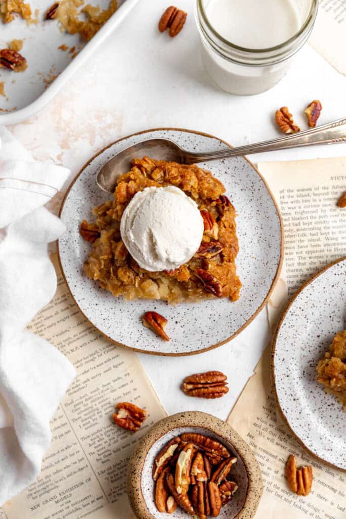 Banana cobbler on a white plate with a scoop of ice cream and a glass of milk.