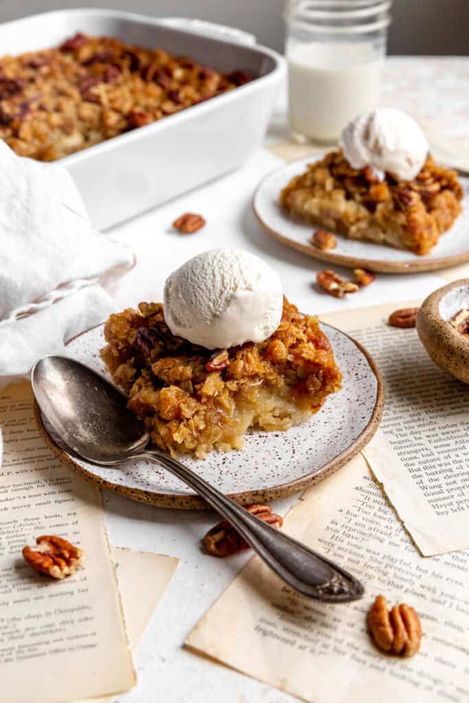 Banana cobbler on white plates, a glass of milk and book pages.