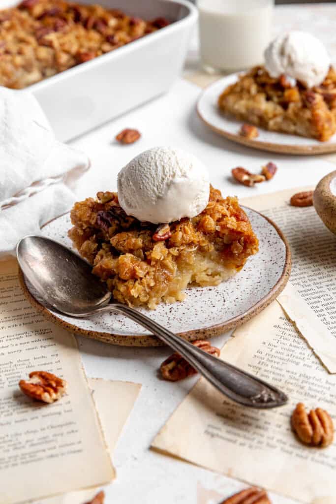 Banana cobbler on white plates, a glass of milk and book pages.