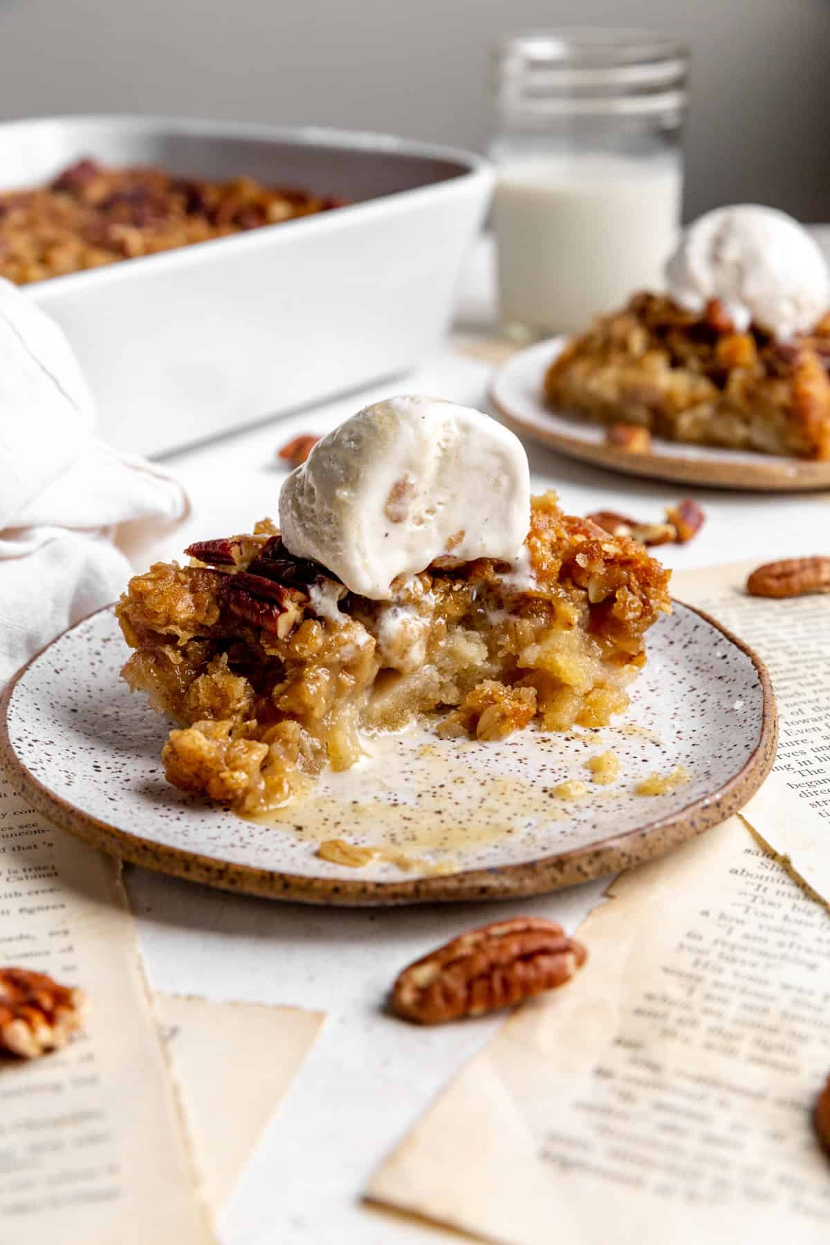 Half eaten banana cobbler and ice cream on a white plate.