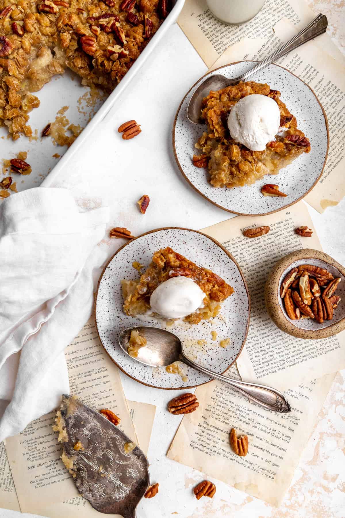 Plates of banana cobbler topped with scoops of vanilla ice cream and a linen napkin.