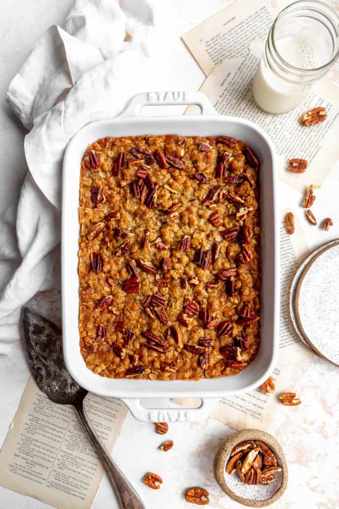 Banana cobbler topped with pecans, a glass of milk and a linen napkin.