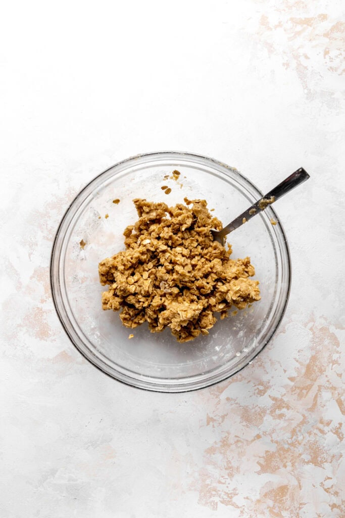 Glass bowl of crumble topping with a spoon.