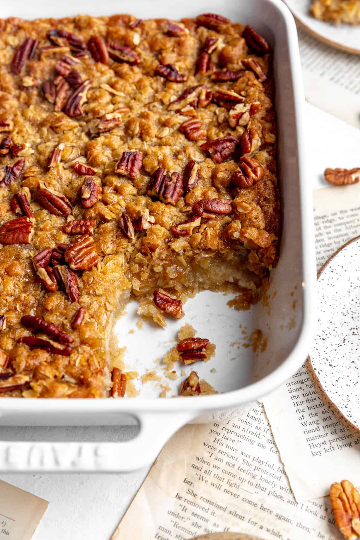 White baking dish of banana cobbler sitting on book pages.
