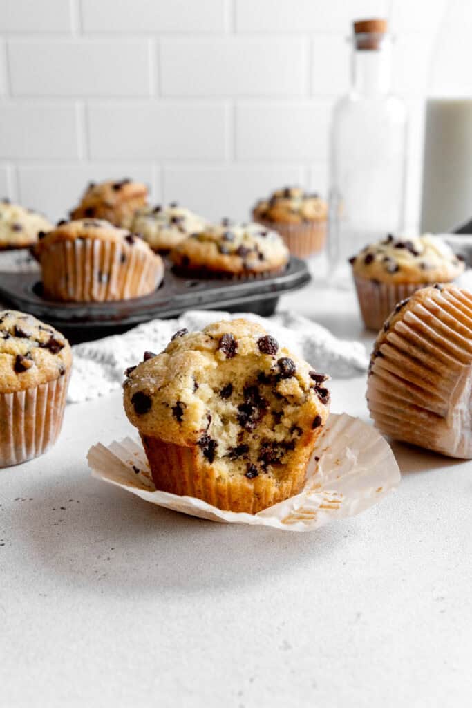 Chocolate chip muffin with a bite taken out of it in front of a jug of milk.