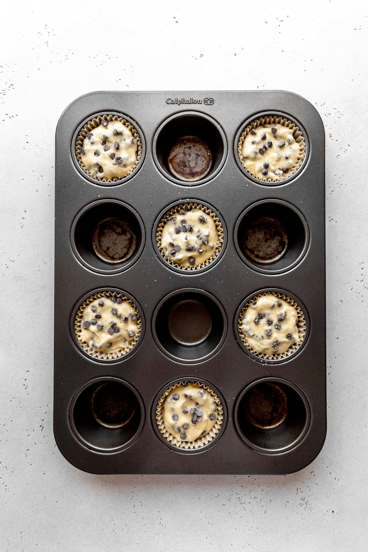 Unbaked chocolate chip muffins in a pan.