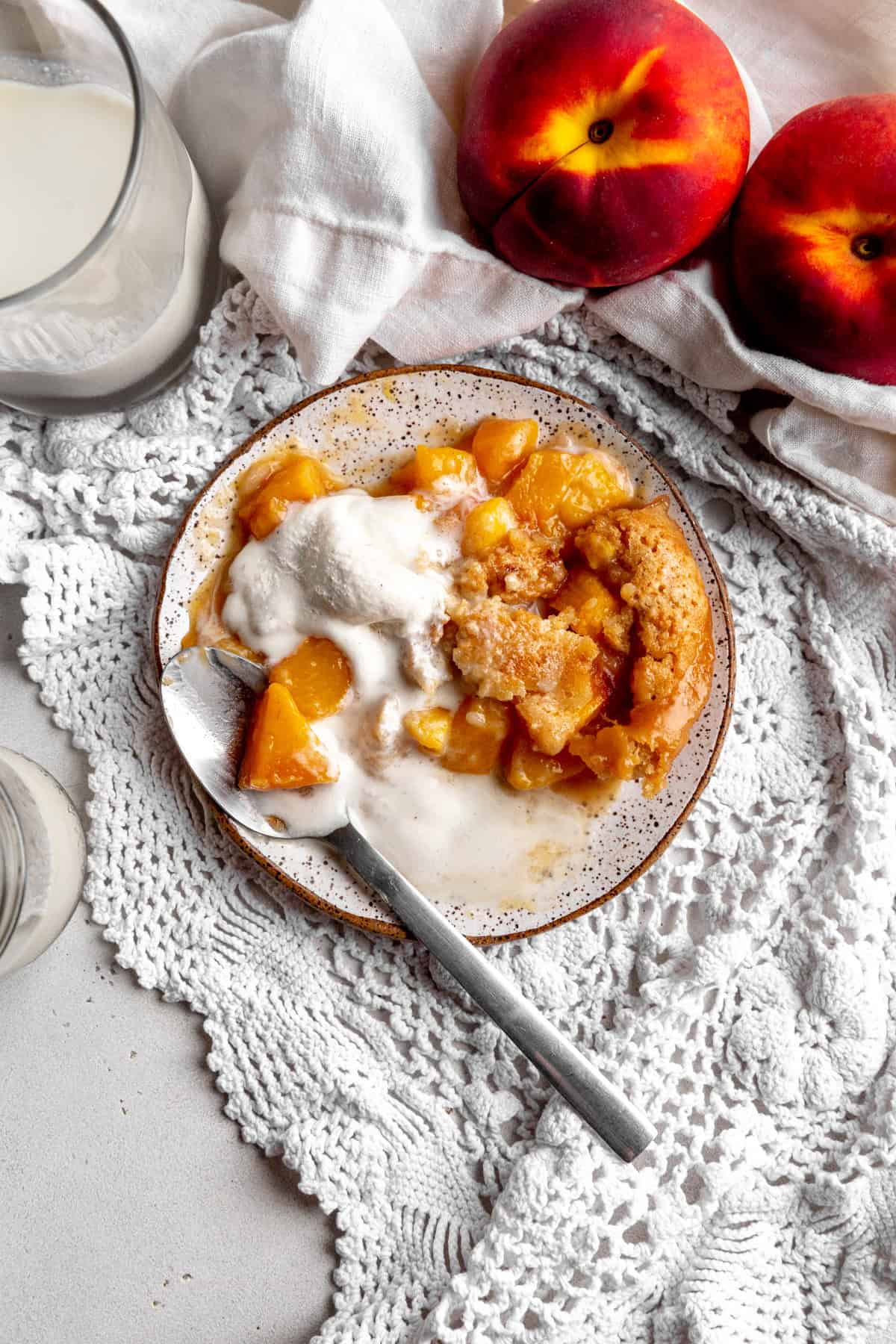 Half eaten peach cobbler on a white plate.