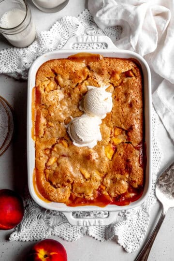 Peach cobbler topped with two scoops of vanilla ice cream and a linen napkin.