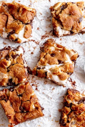 S'mores bars on a white surface and a spoon covered in marshmallow fluff.