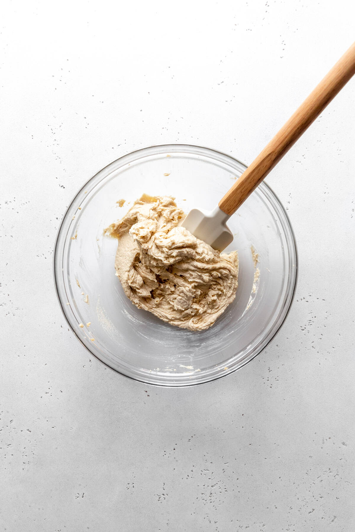 Glass bow of creamed butter and sugar with a rubber spatula.