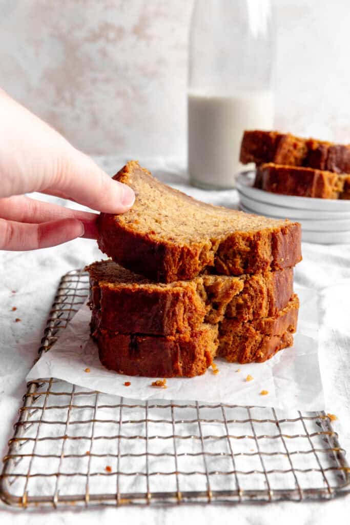Hand lifting a slice of banana bread off of a stack.