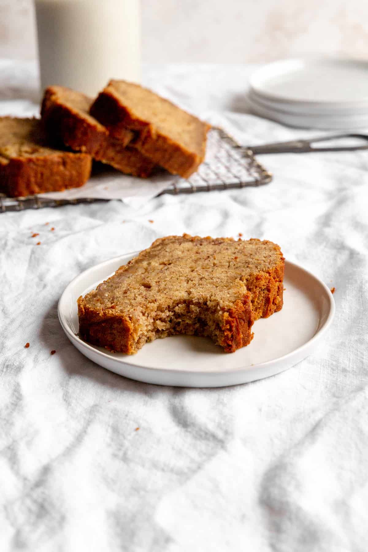 Slice of banana bread with a bite taken out of it on a white plate.