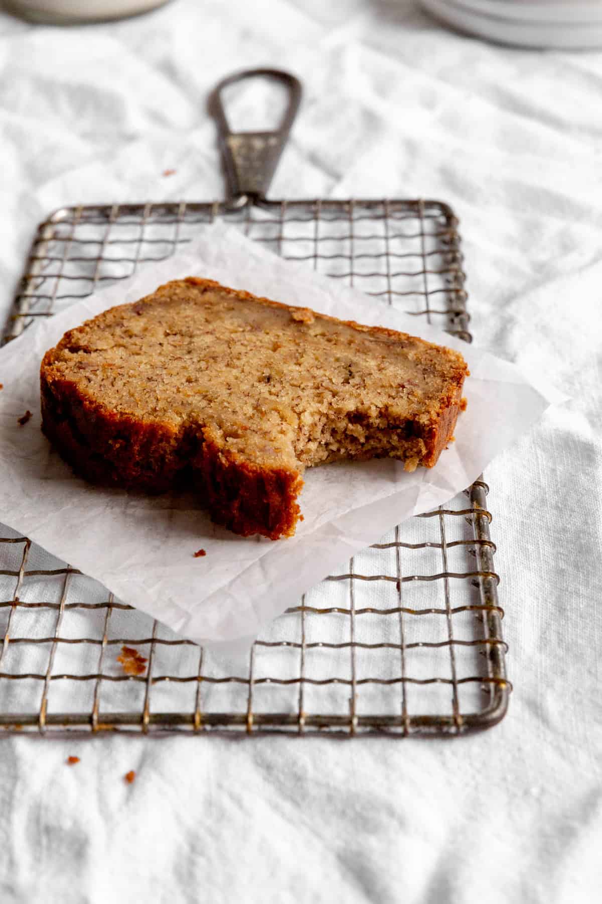 Slice of banana bread with a bite taken out of it on a wire rack.