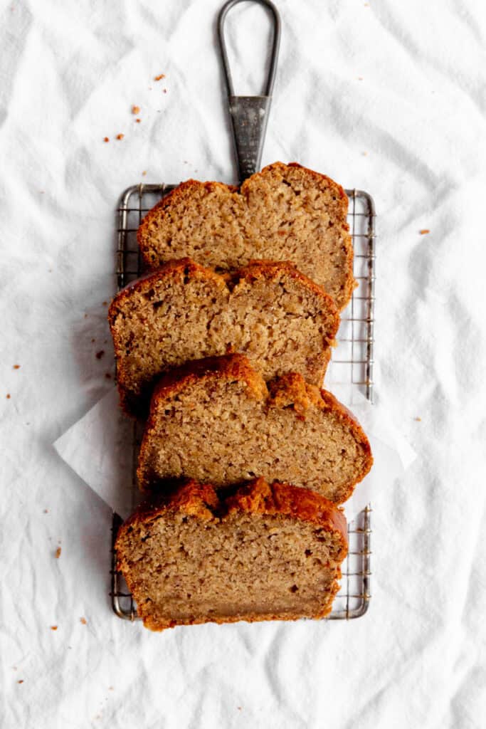 Four slices of banana bread layered on a wire cooling rack.