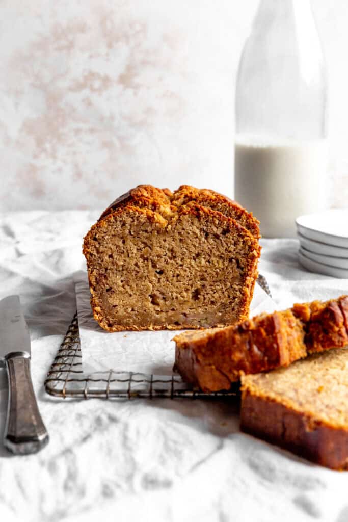 Sliced loaf of banana bread and a jug of milk.