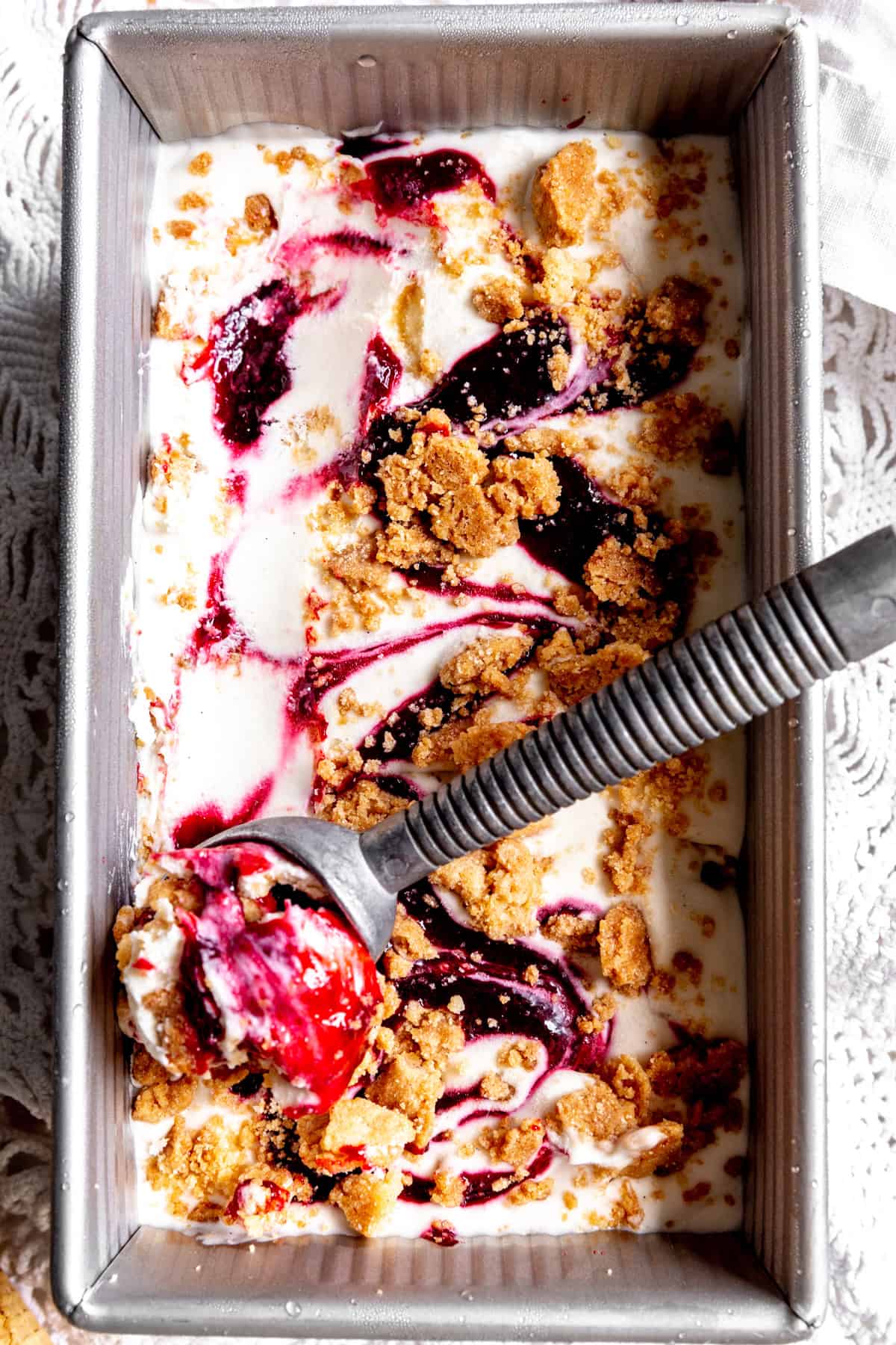 Ice cream scoop in a pan of blackberry cobbler ice cream.