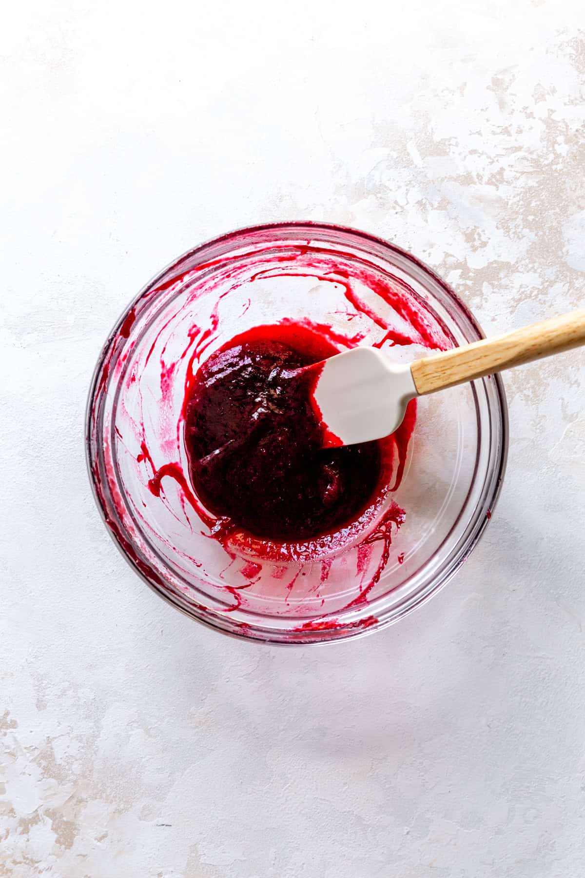 Blackberry compote in a glass bowl and a rubber spatula.