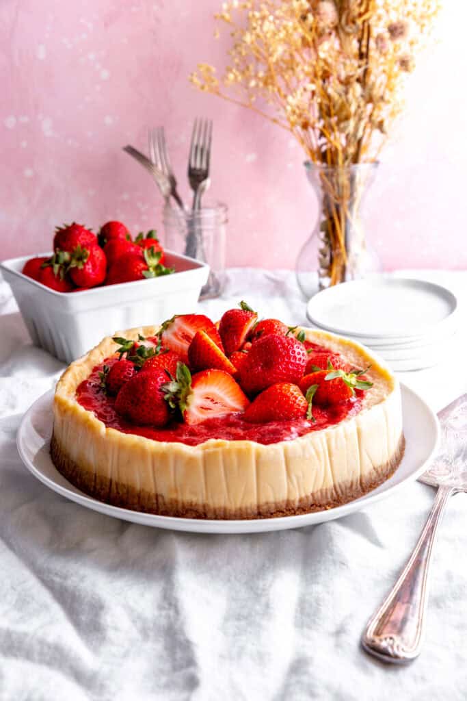 Cheesecake topped with strawberries, and a basket of strawberries.