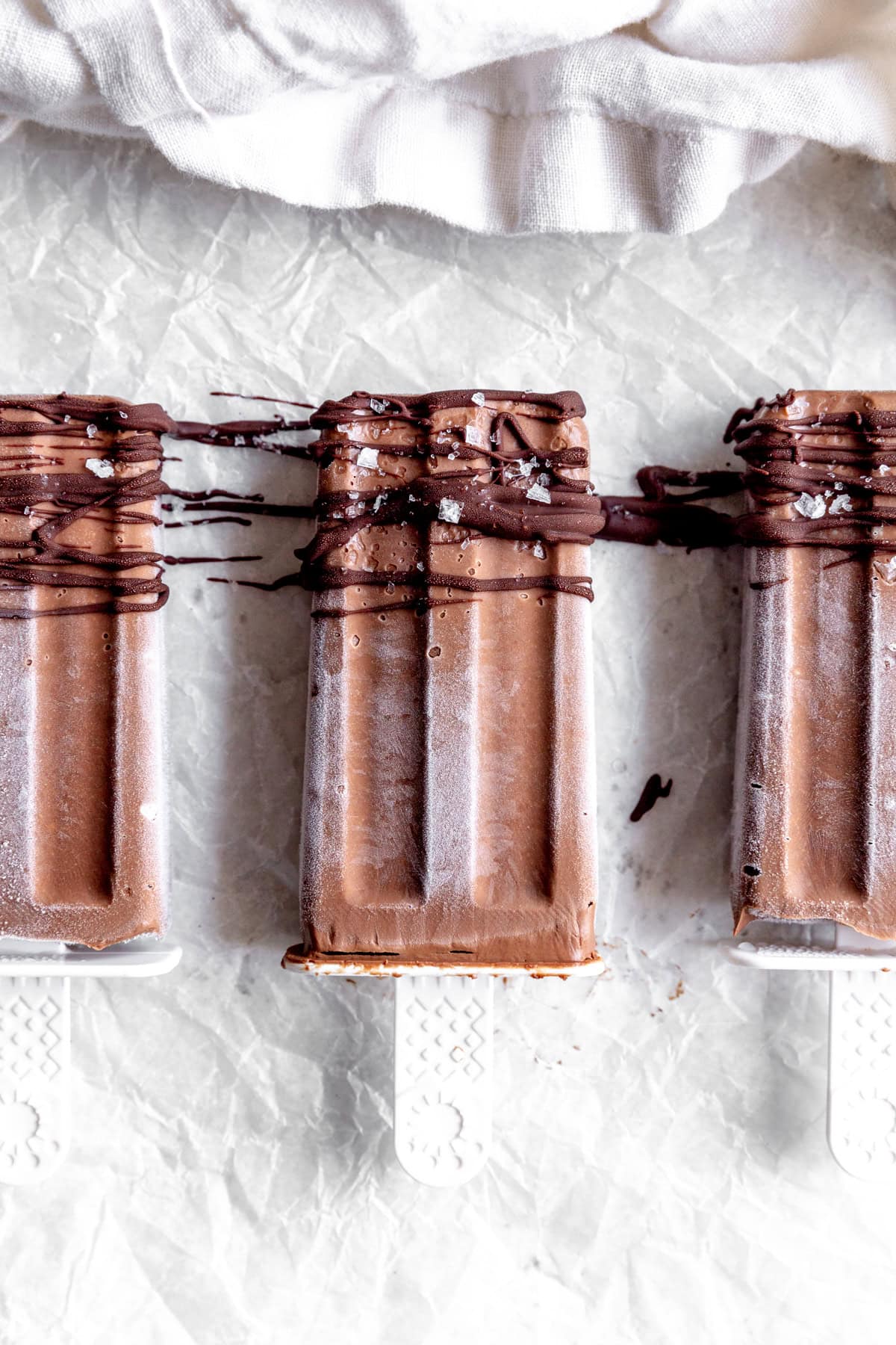 A white linen napkin and fudge pops drizzled in melted chocolate.