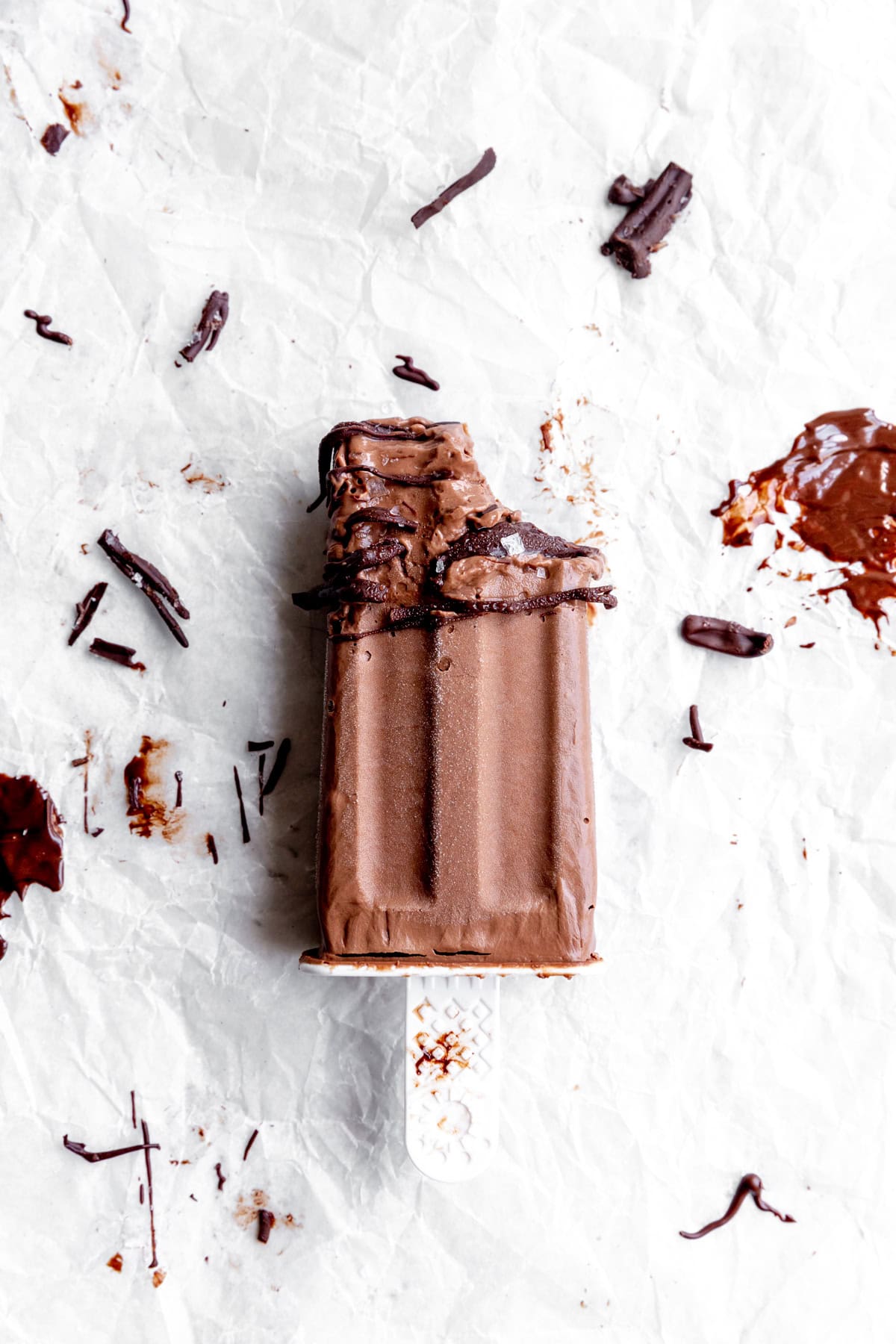 Fudge pop with a bite taken out of it on a sheet of parchment paper.