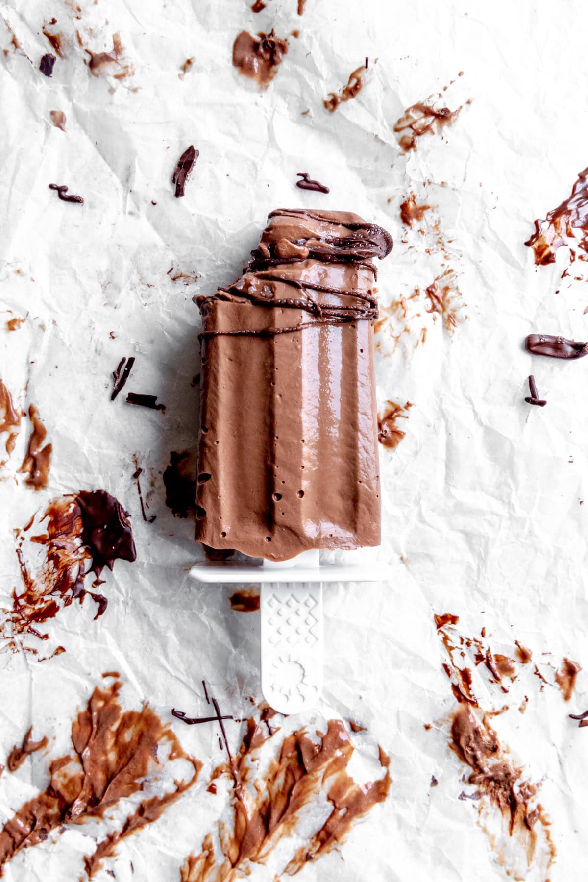 Fudge pop with a bite taken out of it on a white surface.