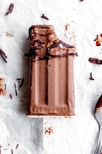 Fudge pop with a bite taken out of it and a spoon covered in chocolate.
