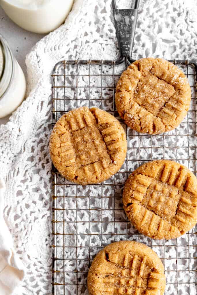 Peanut butter cookies on a wire rack and a glass of milk.