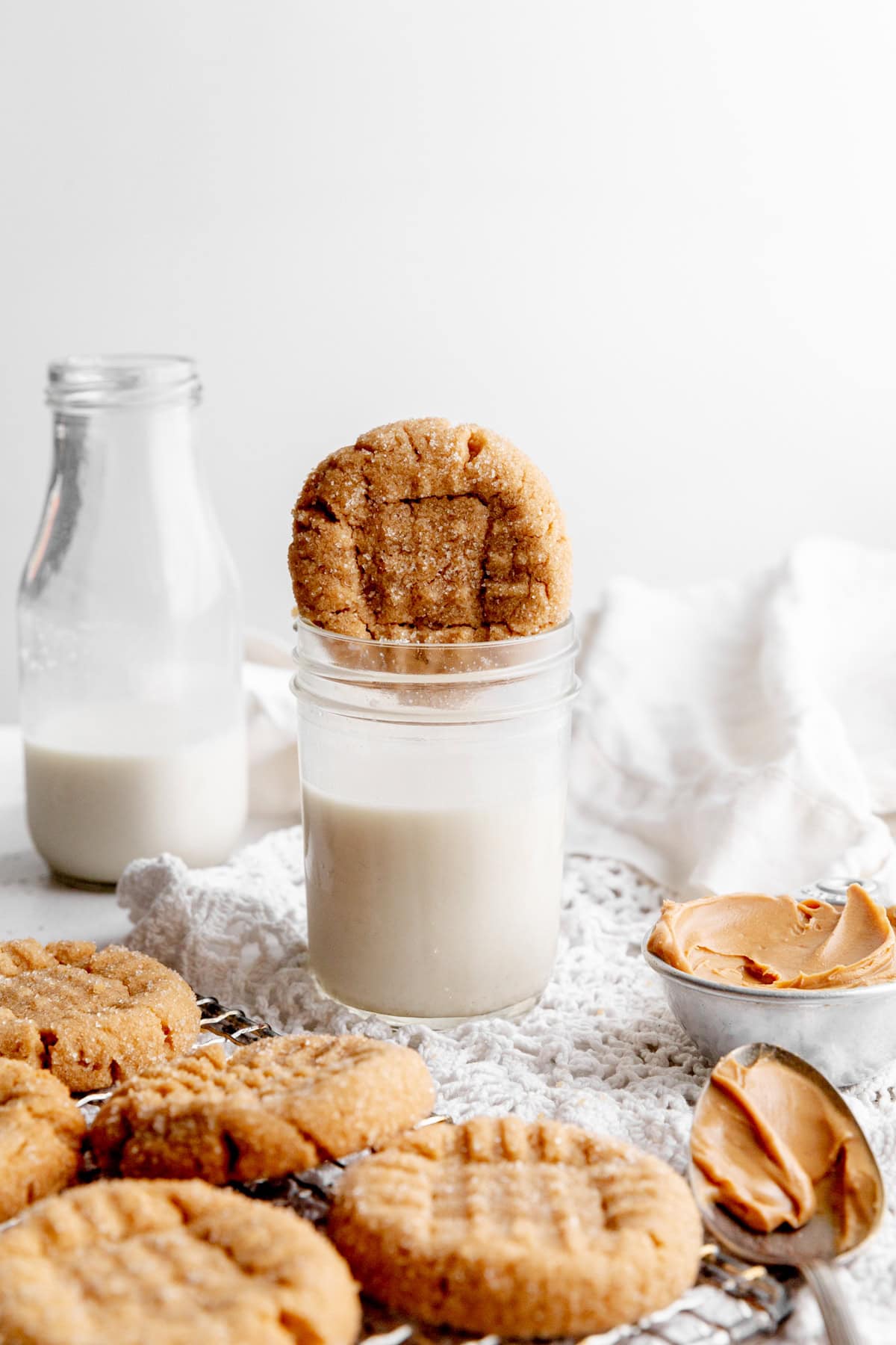 Peanut butter cookie being dunked into a glass of milk.