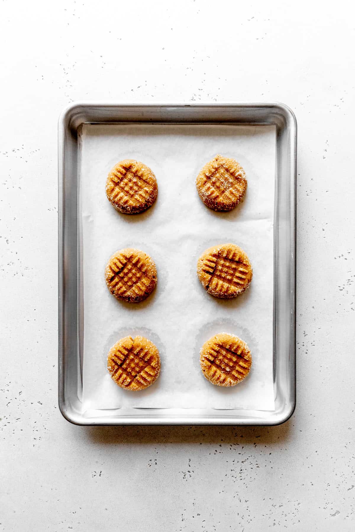 Unbaked peanut butter cookies on a baking sheet.