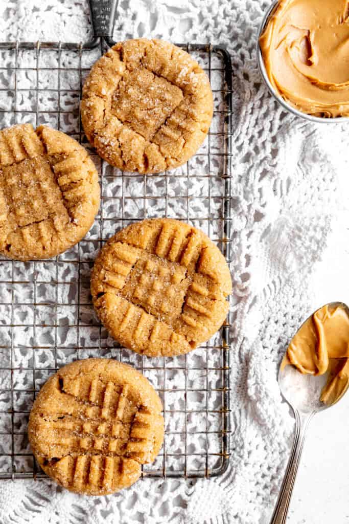 Peanut butter cookies on a wire cooling rack and a spoon covered in peanut butter.