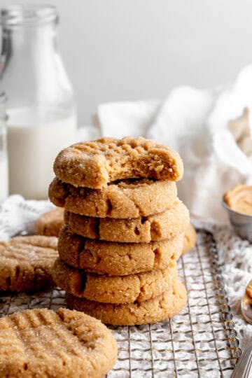 Stack of peanut butter cookies on a wire cooling rack and a jug of milk.