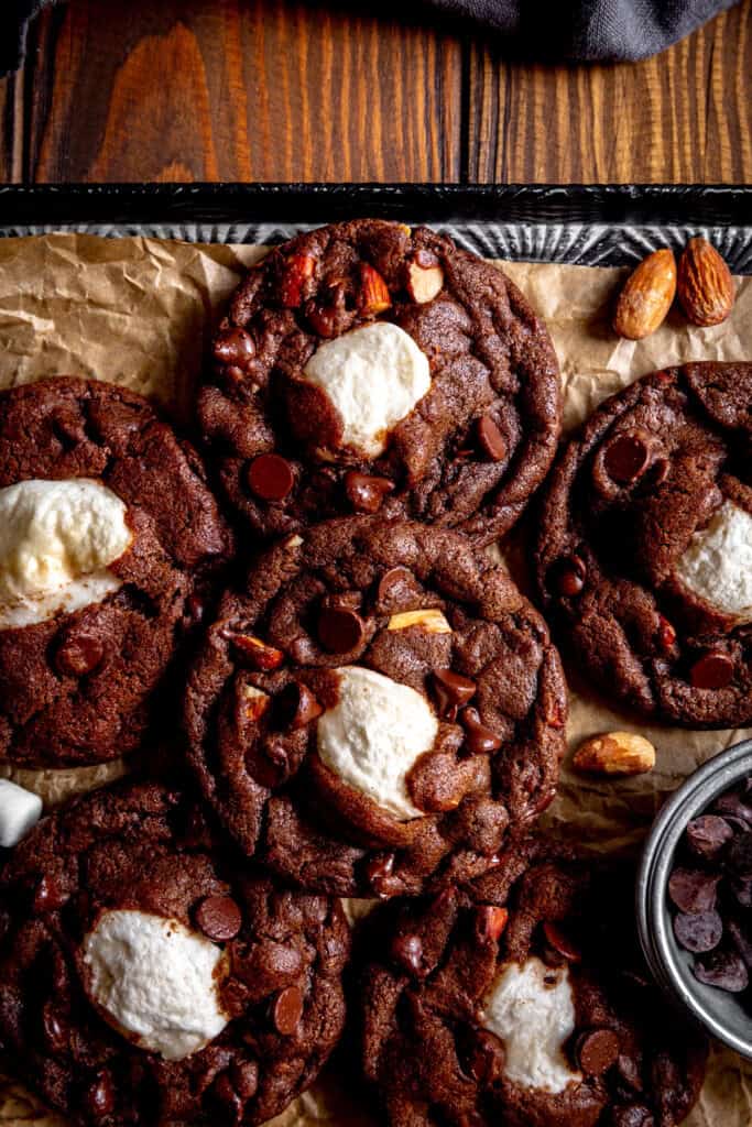 Rocky road cookies on a baking sheet on a wooden tabletop.