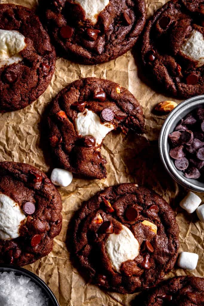 Rocky road cookie with a bite taken out of it and a cup of chocolate chips.