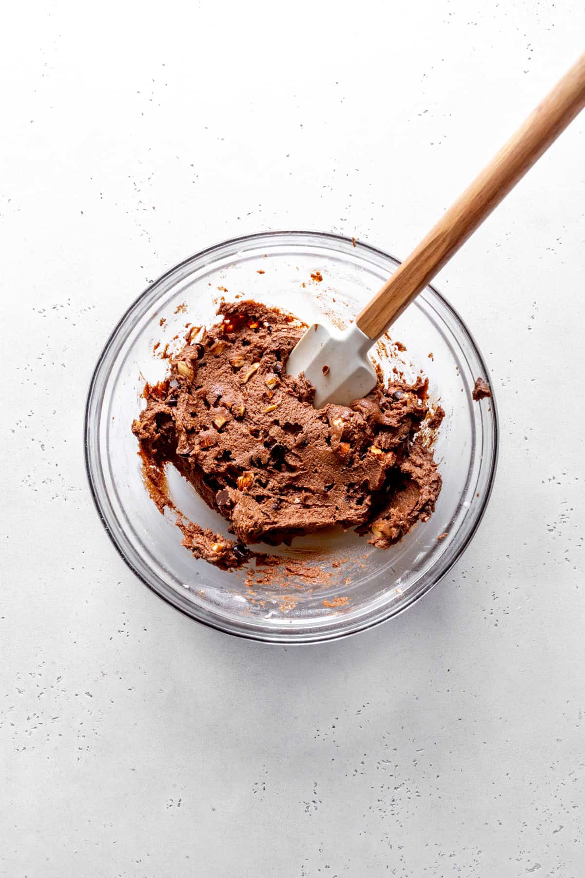 Rocky road cookie dough in a glass bowl with a rubber spatula.
