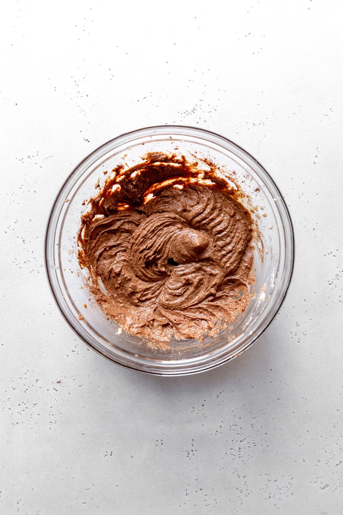 Creamed butter, sugar and cocoa powder in a glass bowl.