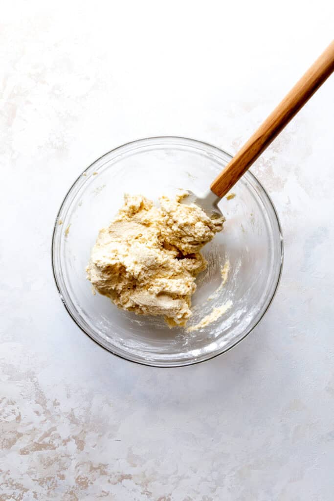 Glass bowl of sugar cookie dough and a rubber spatula.