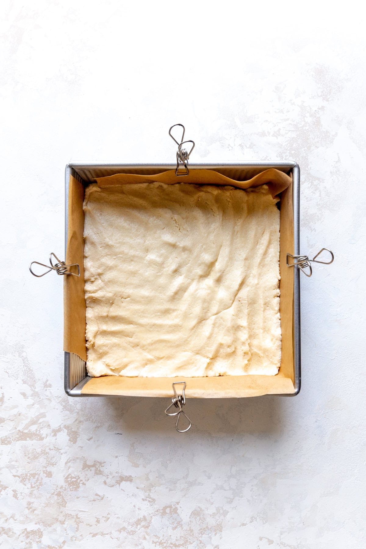 Unbaked sugar cookie dough pressed into a square pan.