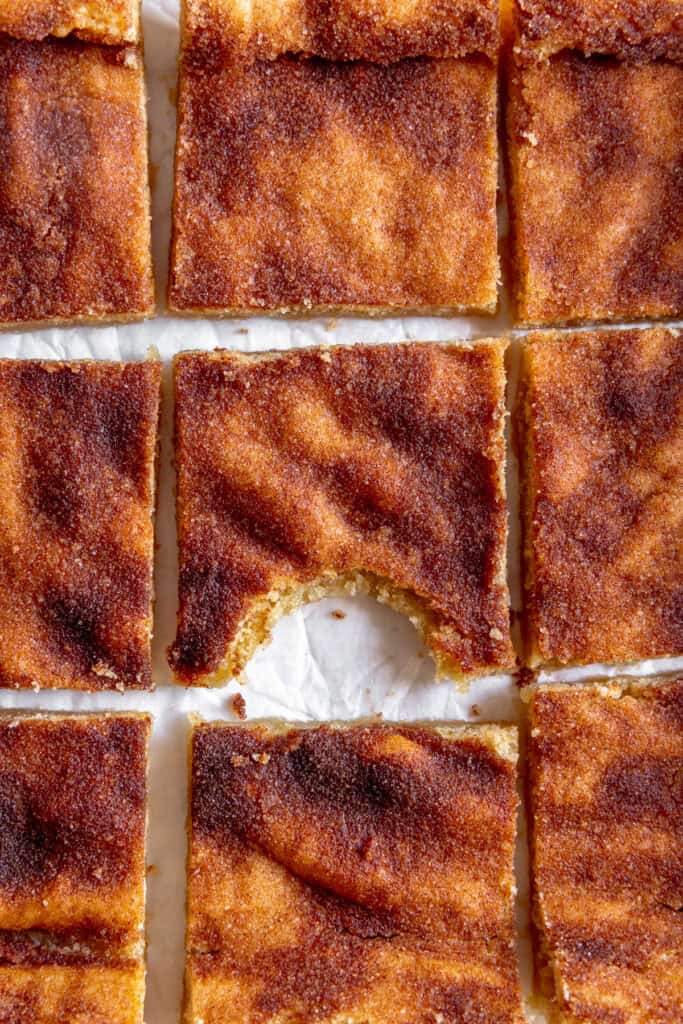 Snickerdoodle bars arranged in a square, then center bar has a bite taken out of it.
