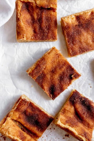Snickerdoodle bars spread out on white parchment paper.