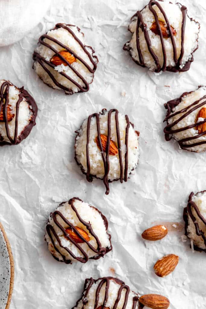 Almond joy bites on a white surface and scattered almonds.