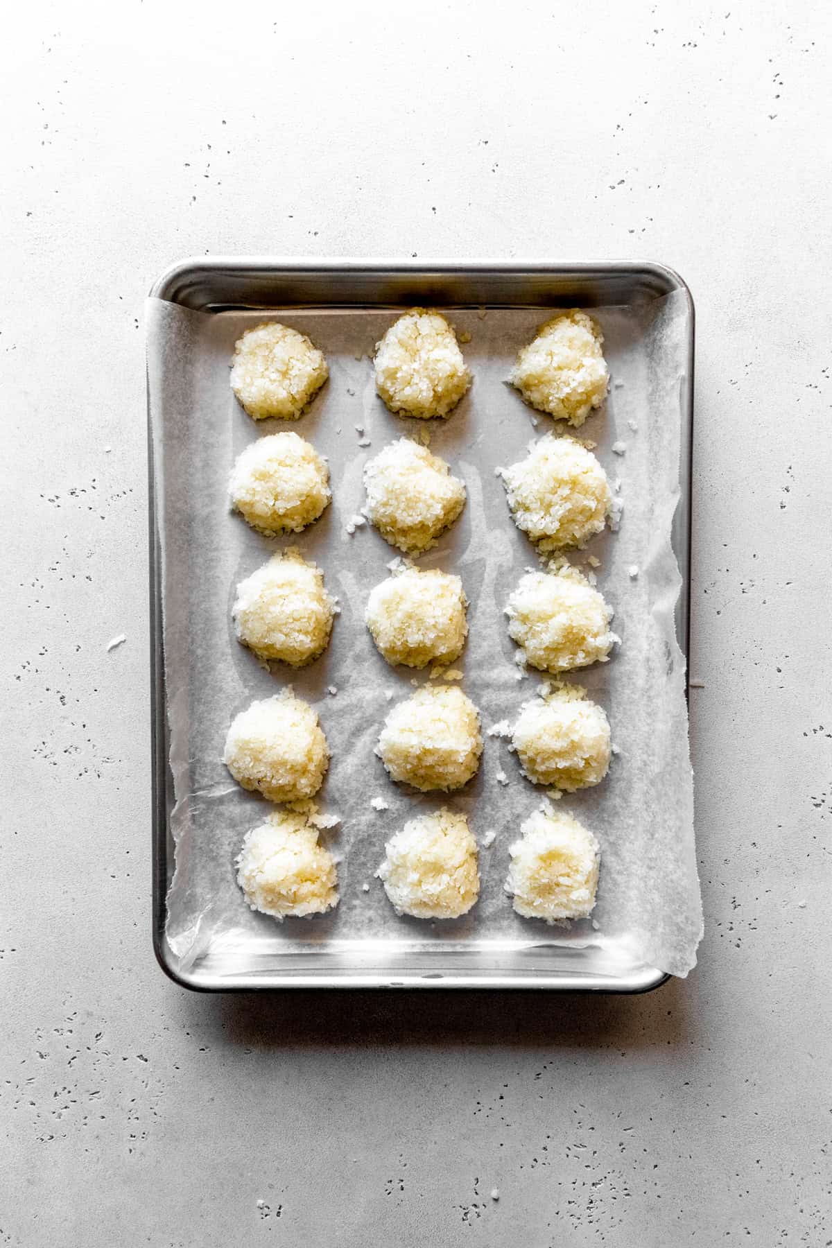 Scoops of coconut filling laid out on a baking sheet.