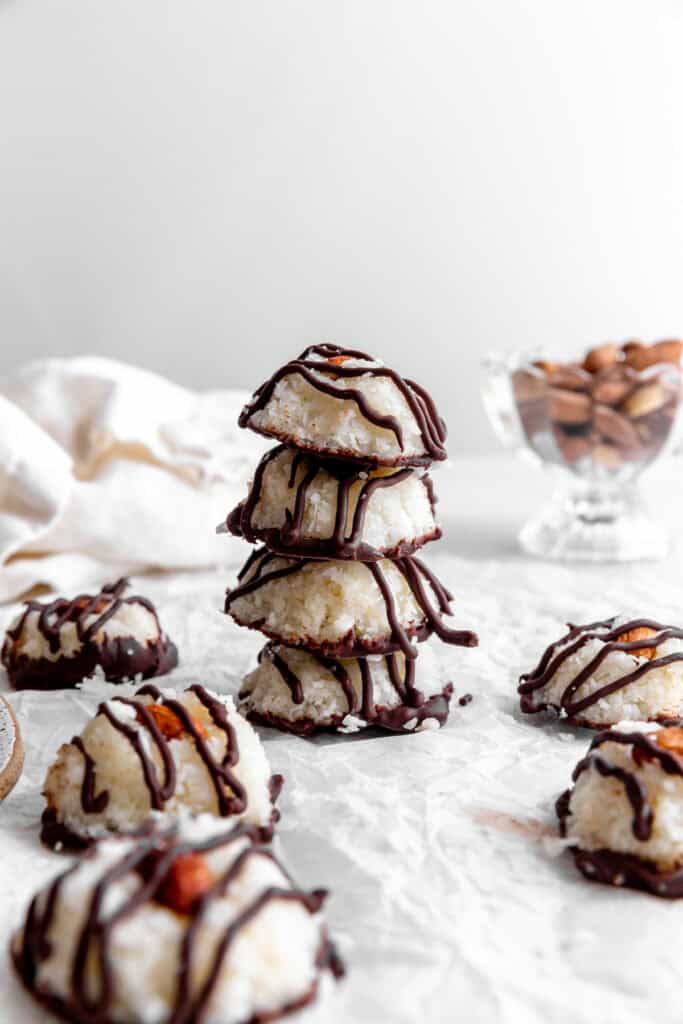 Stack of vegan almond joys, a linen napkin and a dish of almonds.