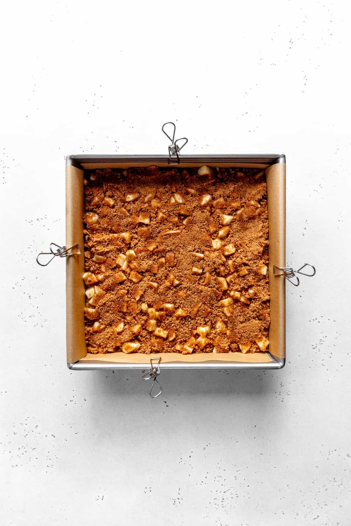 Diced apples and brown sugar in a square baking pan.