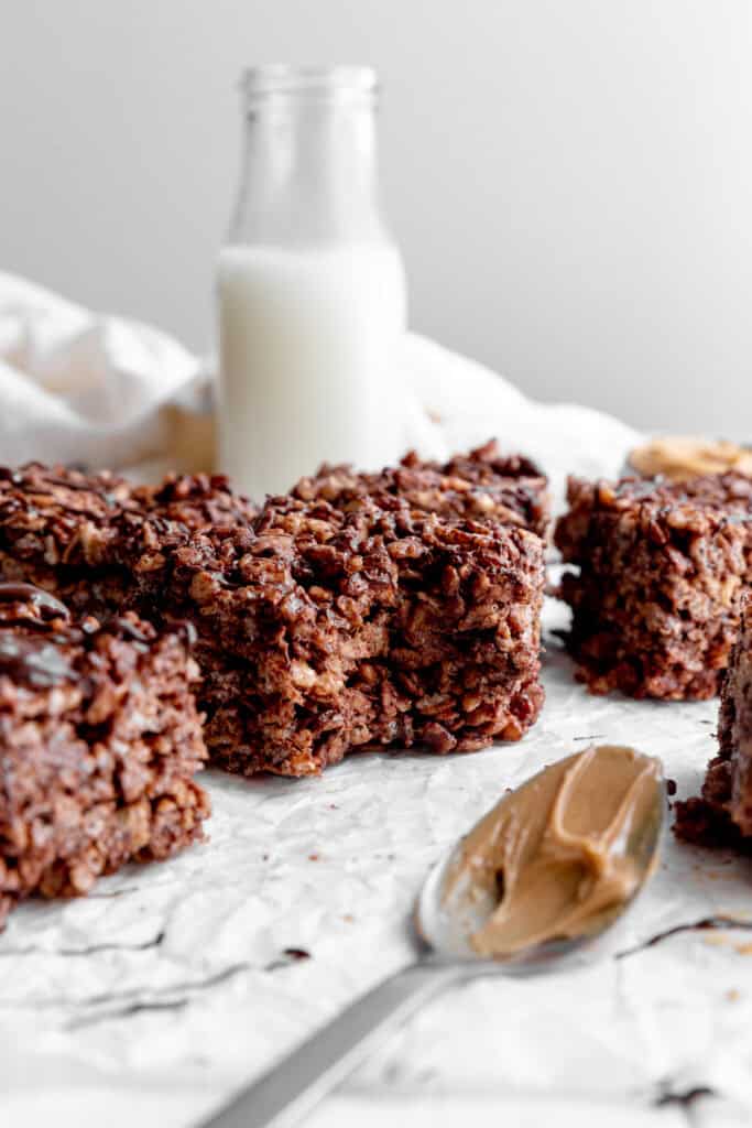 Chocolate peanut butter rice krispie treat with a bite taken out of it and a jug of milk.
