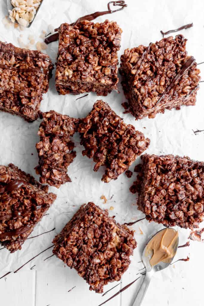Chocolate peanut butter rice krispie treat torn in half on a white surface.