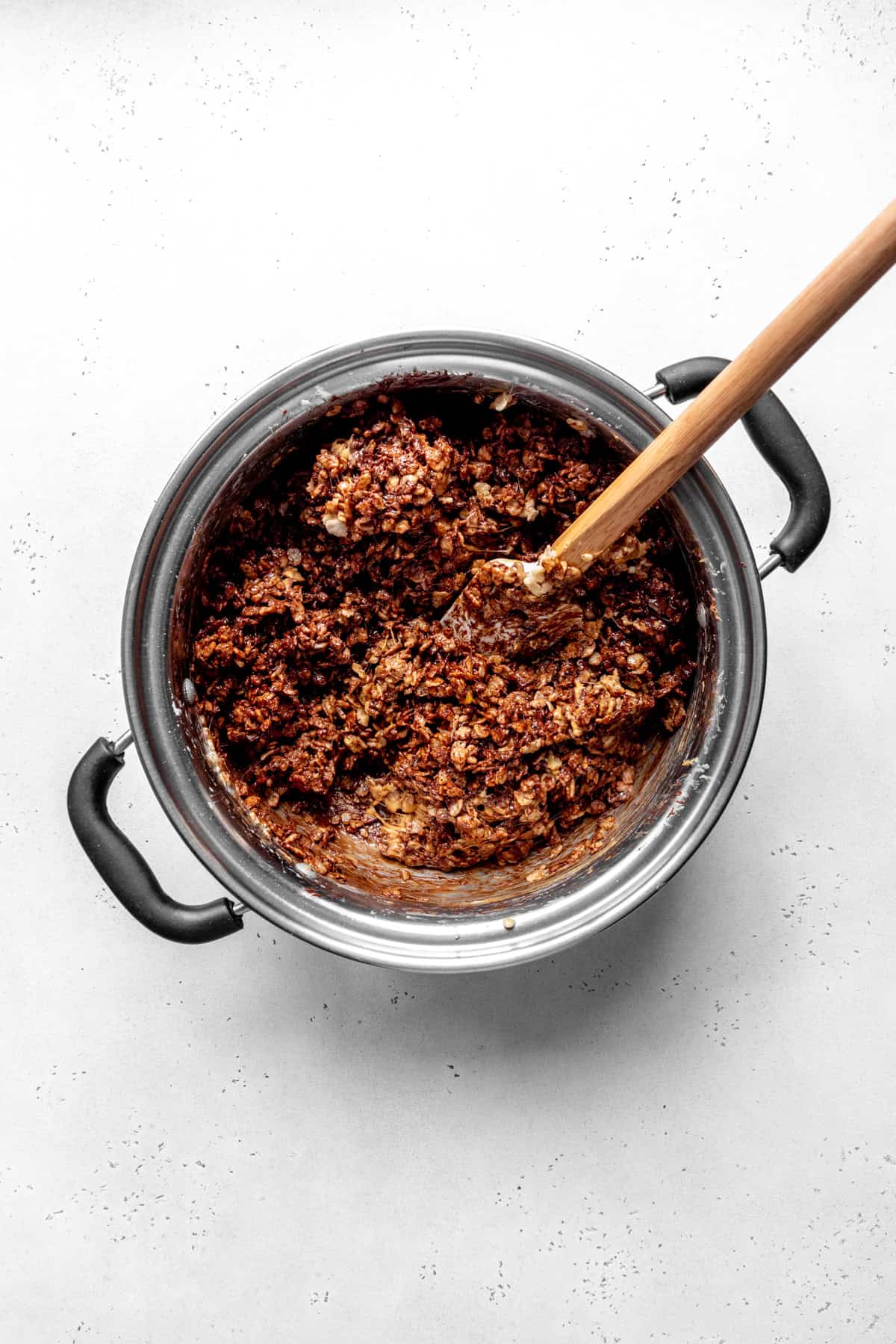 Crispy rice cereal, chocolate and peanut butter in a pot with a rubber spatula.