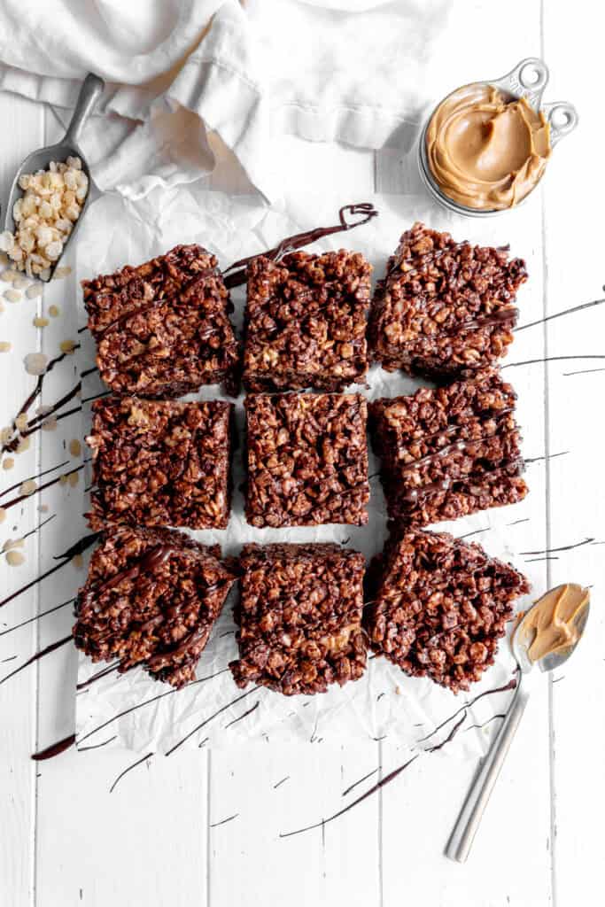 Chocolate peanut butter rice krispie treats drizzled in chocolate and a cup of peanut butter.