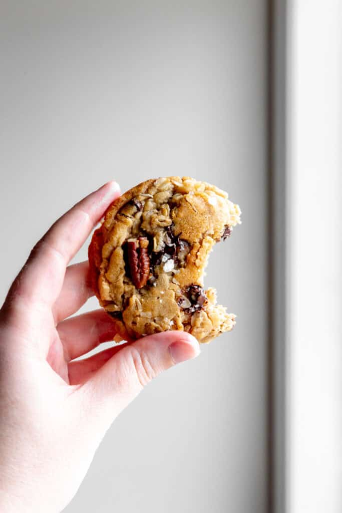 Hand holding a cowboy cookie with a bite taken out of it.