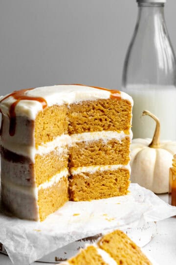 Pumpkin layer cake, a jug of milk, a white pumpkin and a jar of caramel sauce.