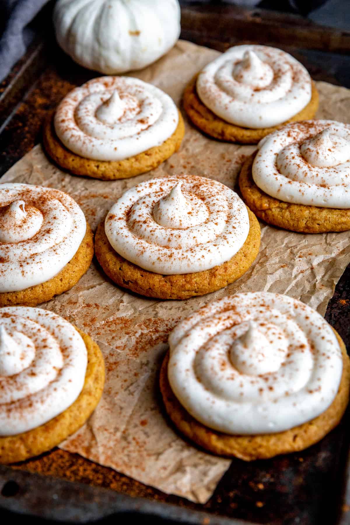 Pumpkin cookies topped with a swirl of cream cheese frosting.